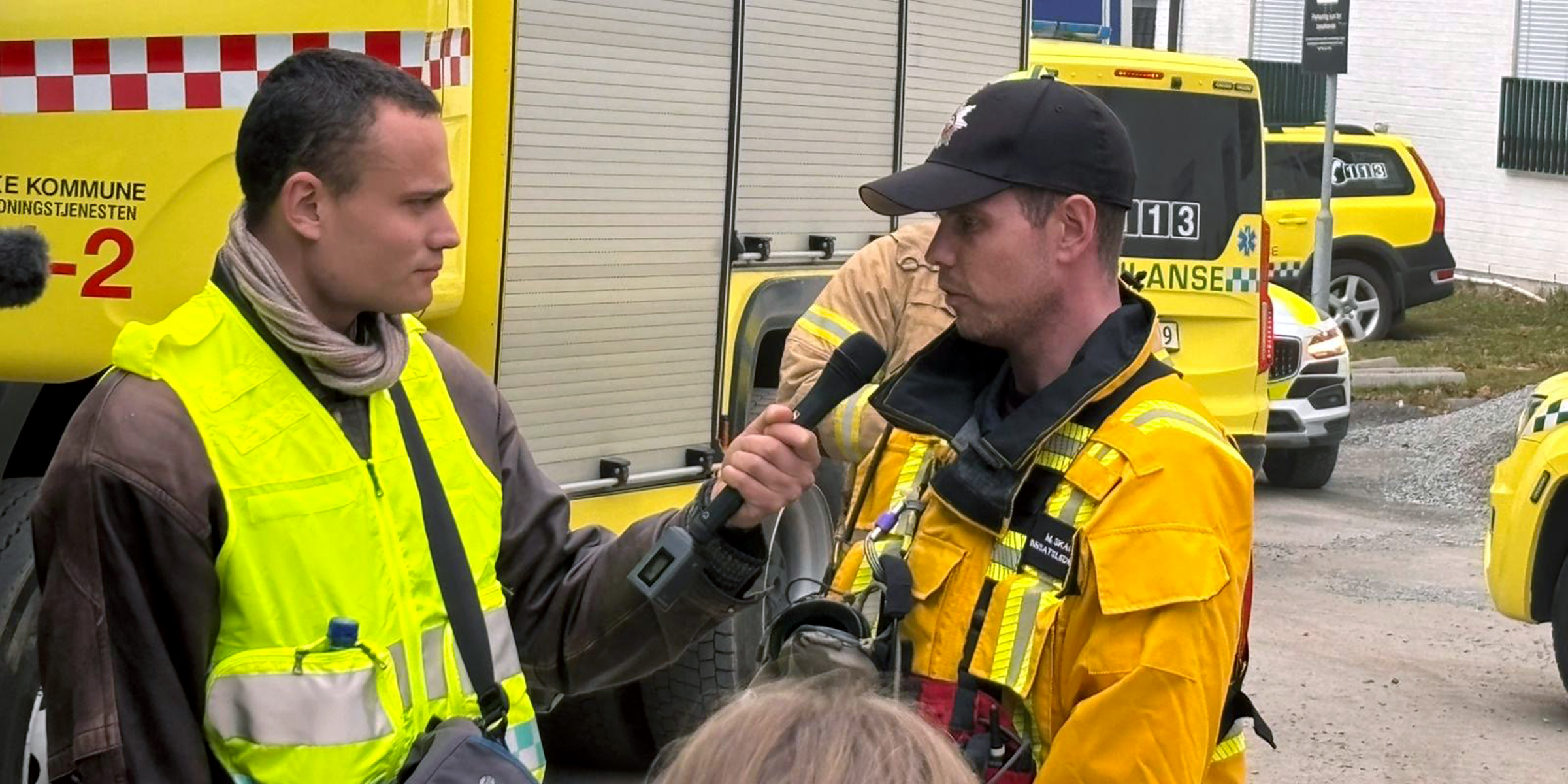 Mannleg journaliststudent intervjuar mannleg representant frå brannvesenet. I bakgrunner er både brannbil og ambulanse.