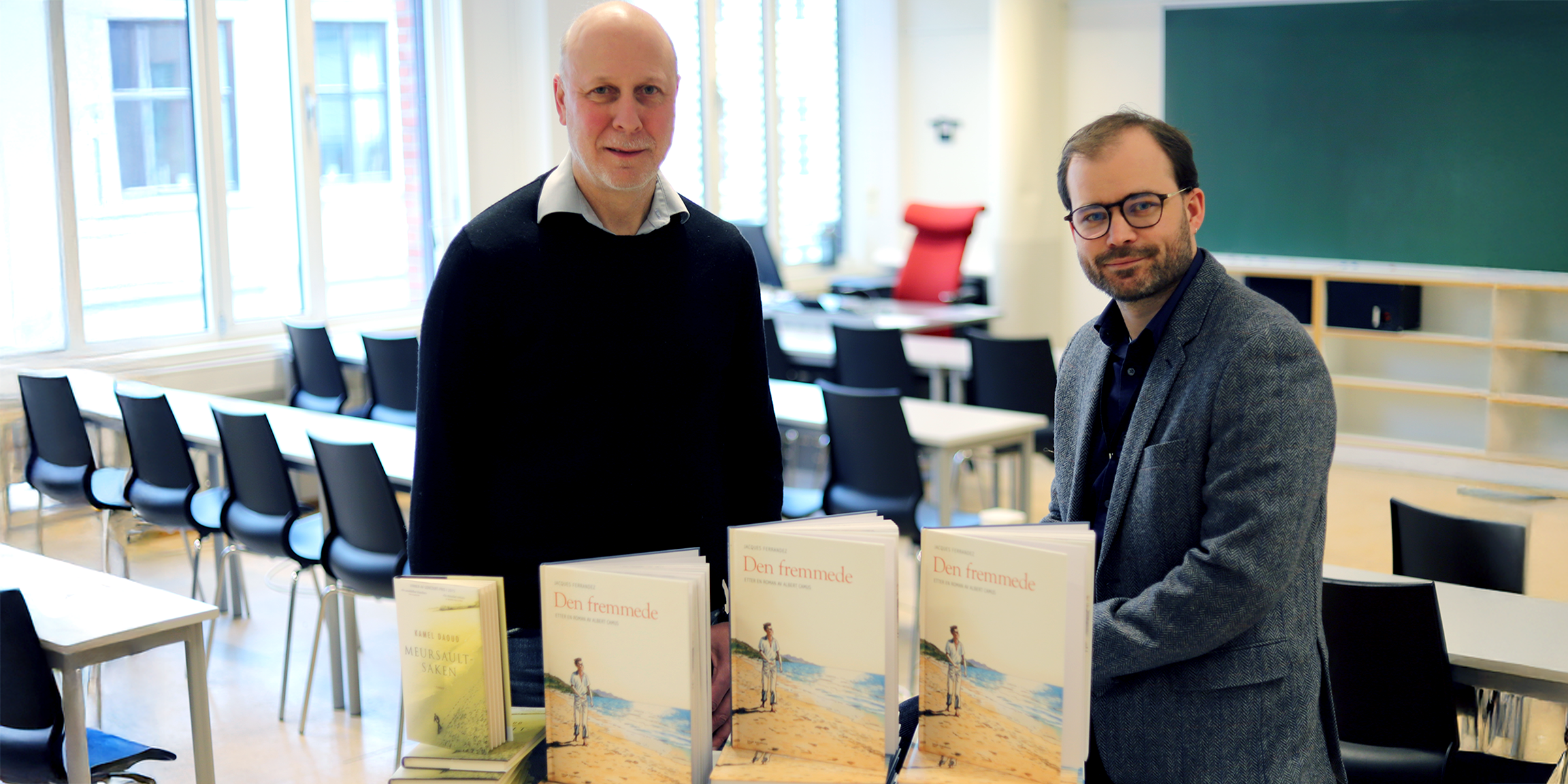 Knut Oterholm og Pål Csaszni Halvorsen i eit undervisningsrom, bak eit bord med bøker.