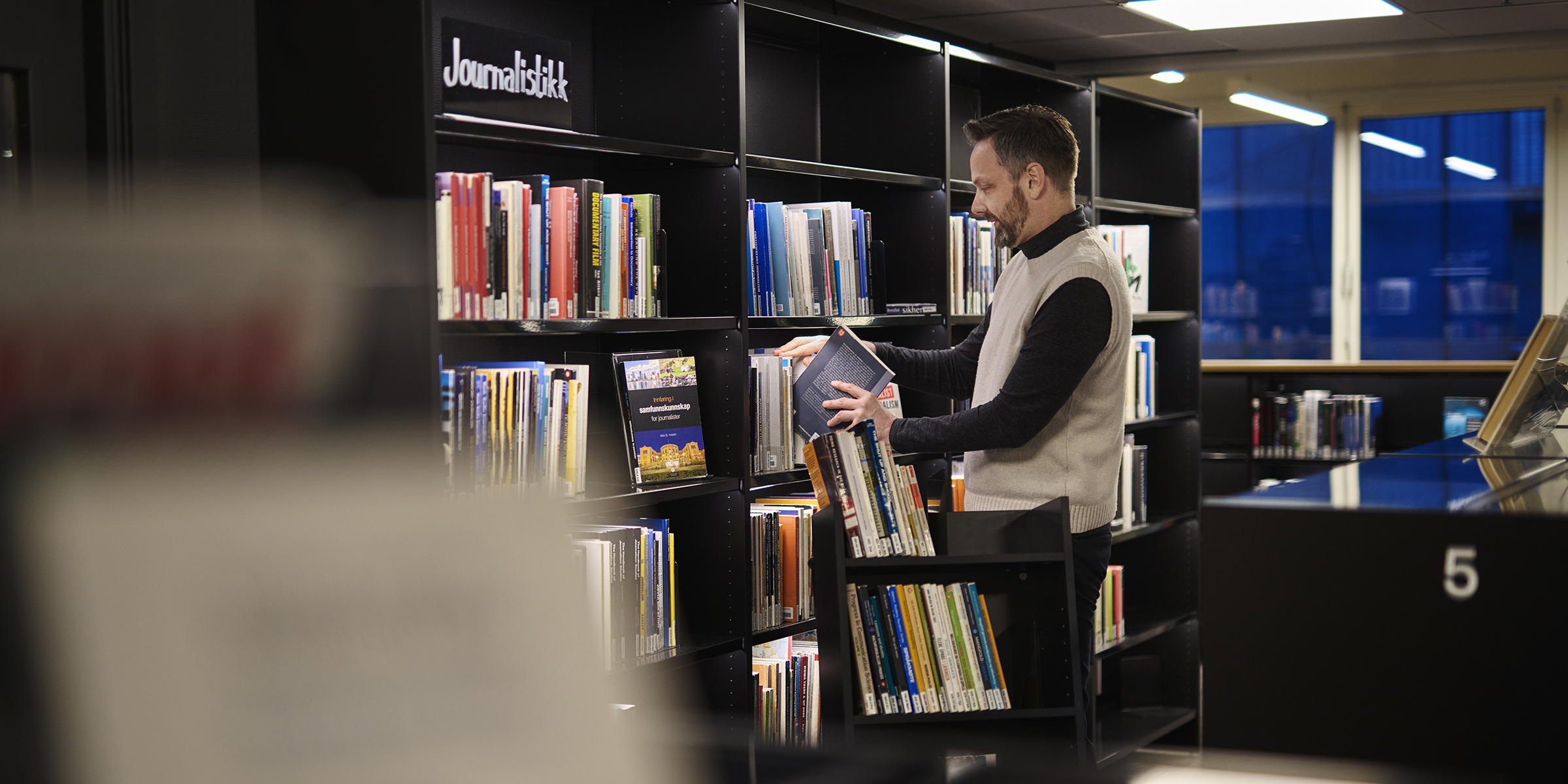 Bibliotekar setter på plass bøker.