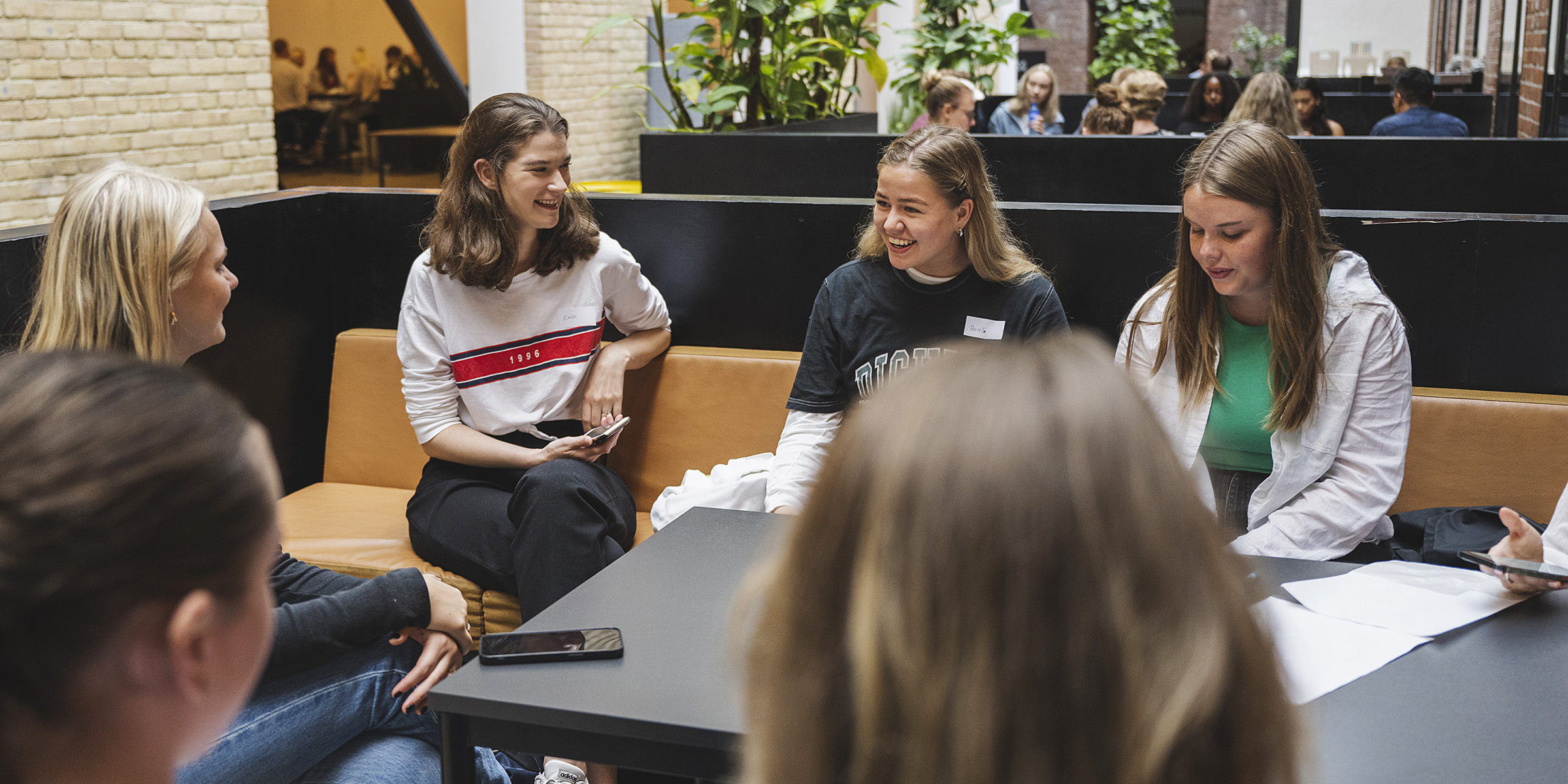 Studenter sitter i en ring rundt et bord og smiler