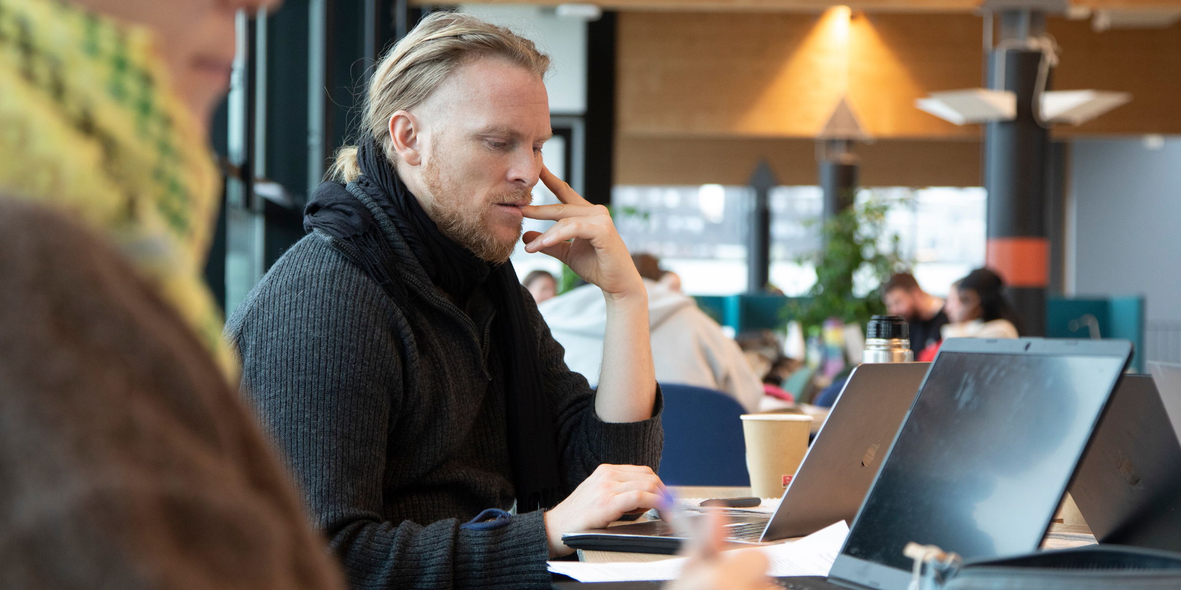 Student leser med laptopen foran seg på bordet.
