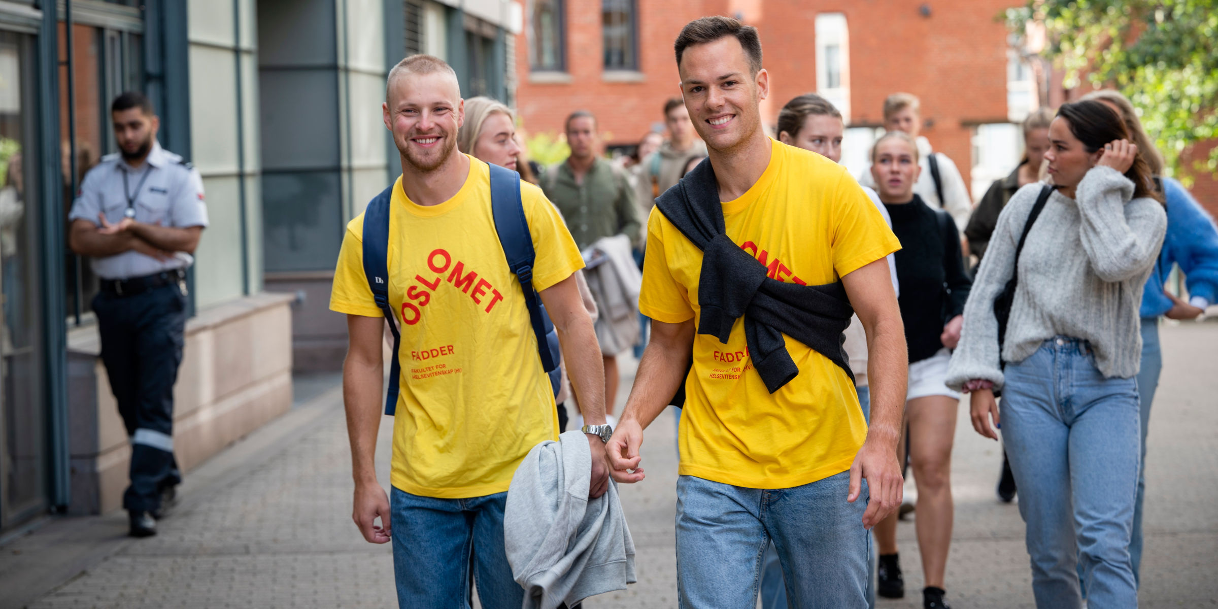 Foto av to faddere som leder en gruppe nye studenter oppover campus Pilestredet.