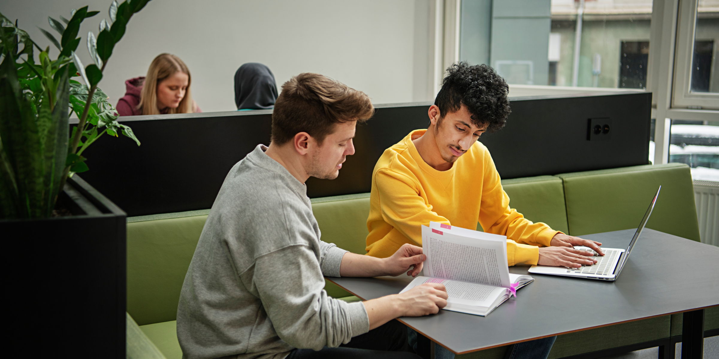 To studenter sitter rundt et bord og samarbeider.