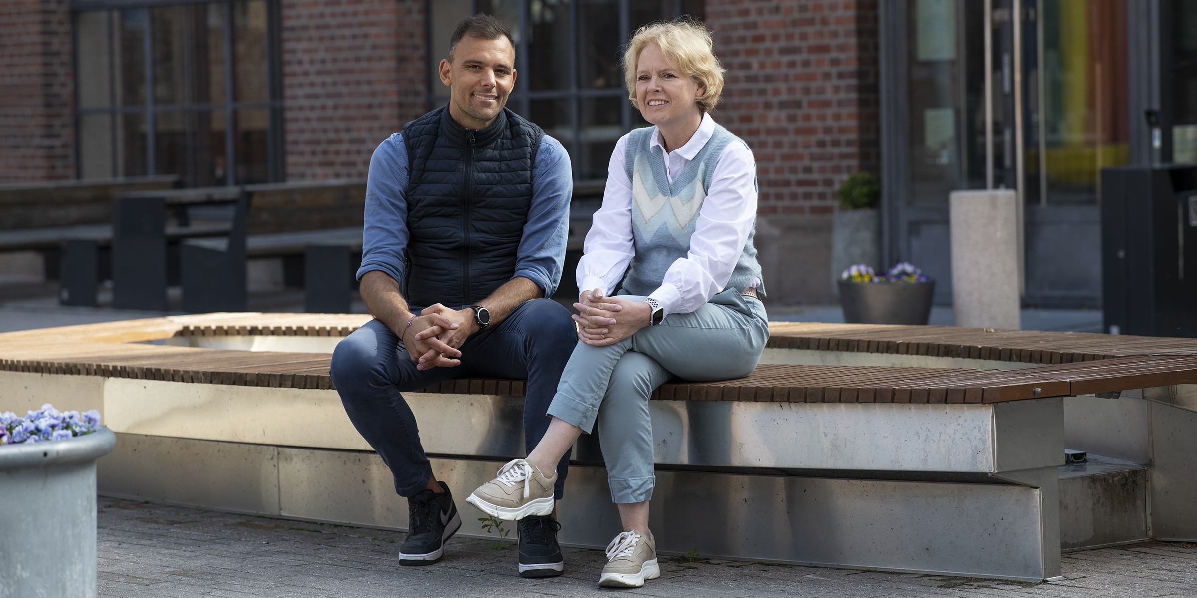 Foto av Carl Christian Thodesen og Marianne Aasen sittende på en benk foran bygg på campus Pilestredet.
