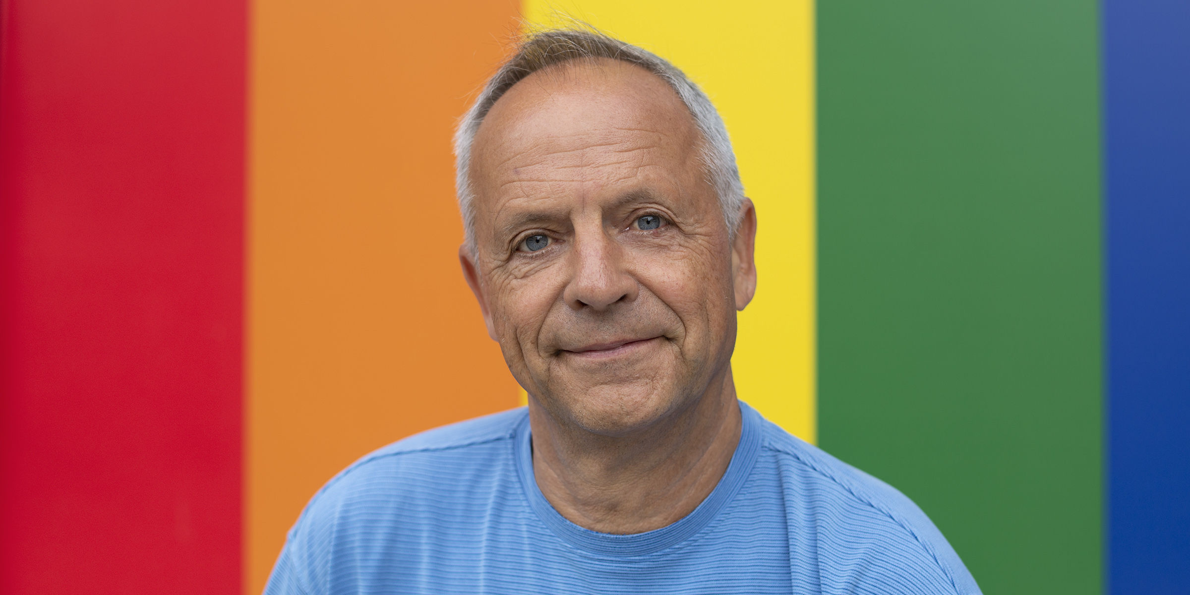Bilde av Anders Gjesvik med Pride-flagget bak.