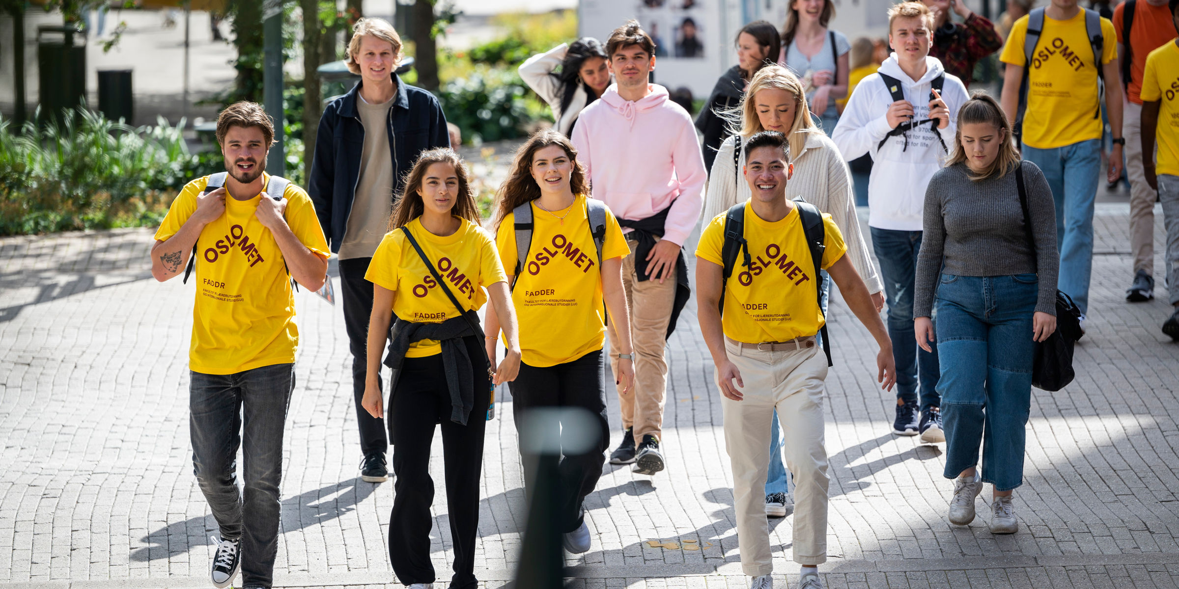 En gruppe gående unge mennesker kledd i gule t-skjorter og vanlige klær.