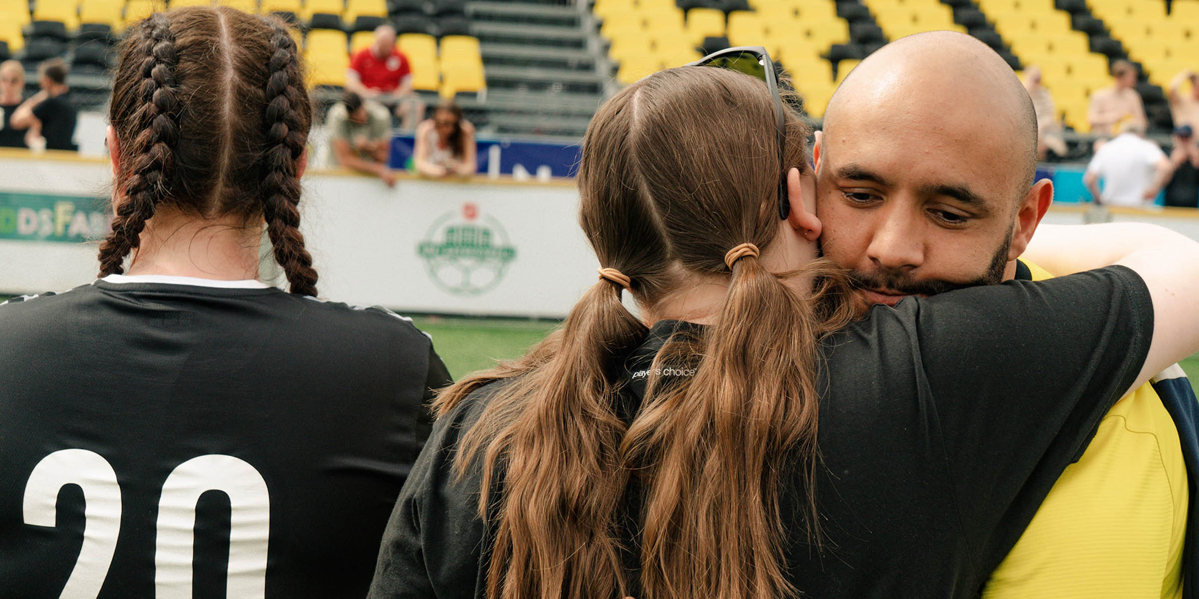 En mann omfavner en kvinne med svart fotballdrakt.