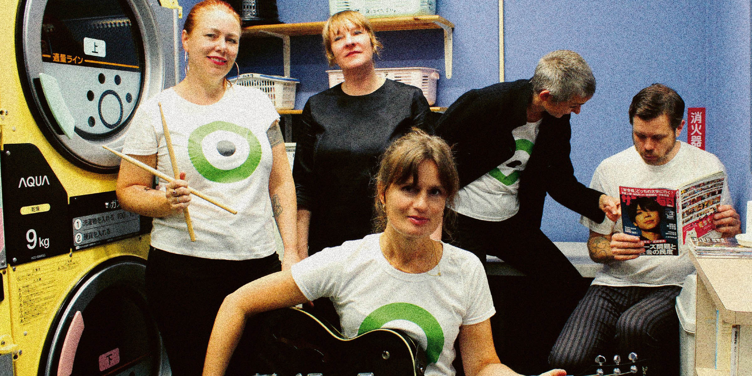 Foto av bandet The Launderettes fem medlemmer, sittende inne i et gammeldags vaskeri.