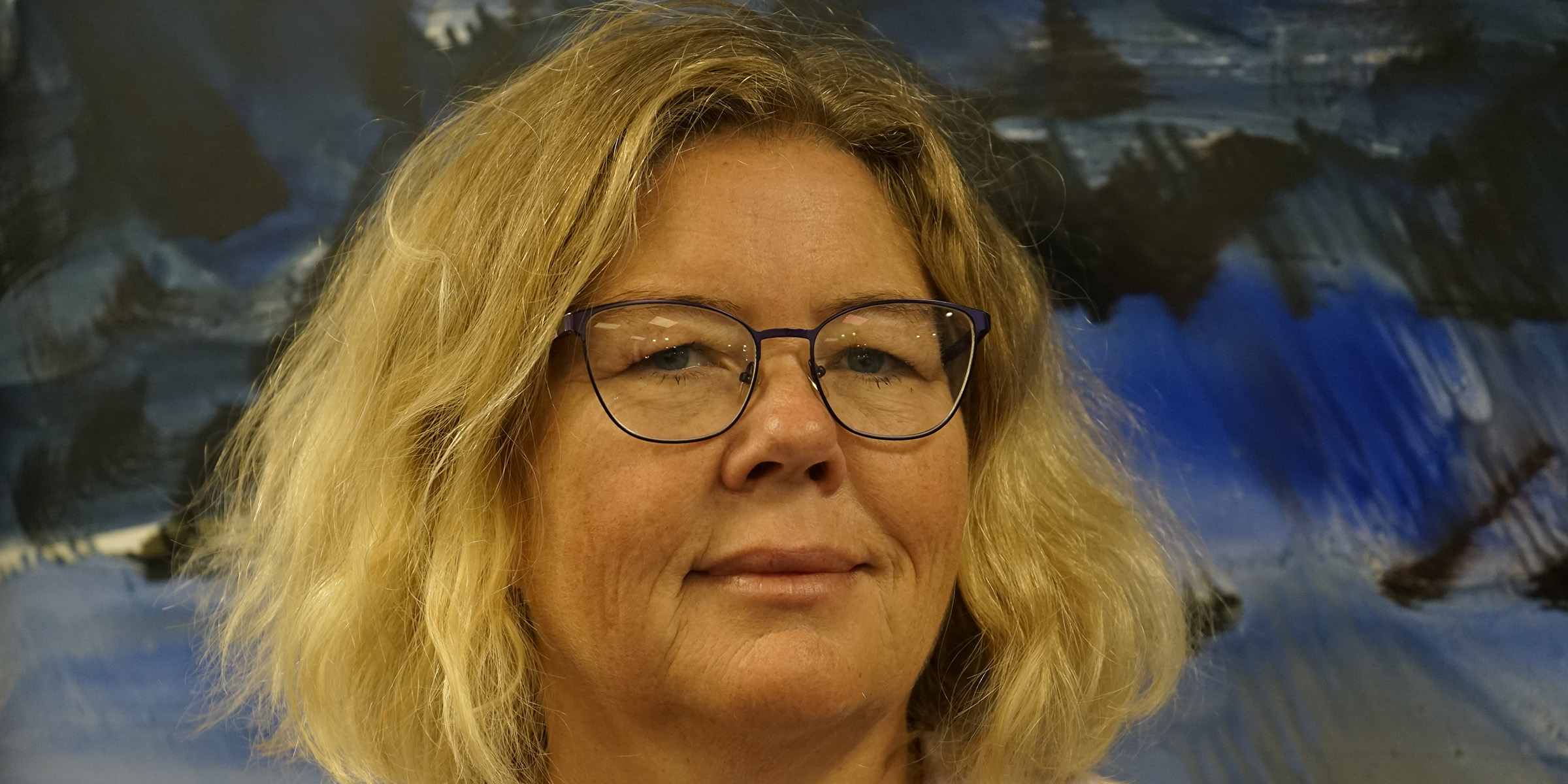 Portrett av førsteamanuensis Randi Havnen som står foran et maleri.