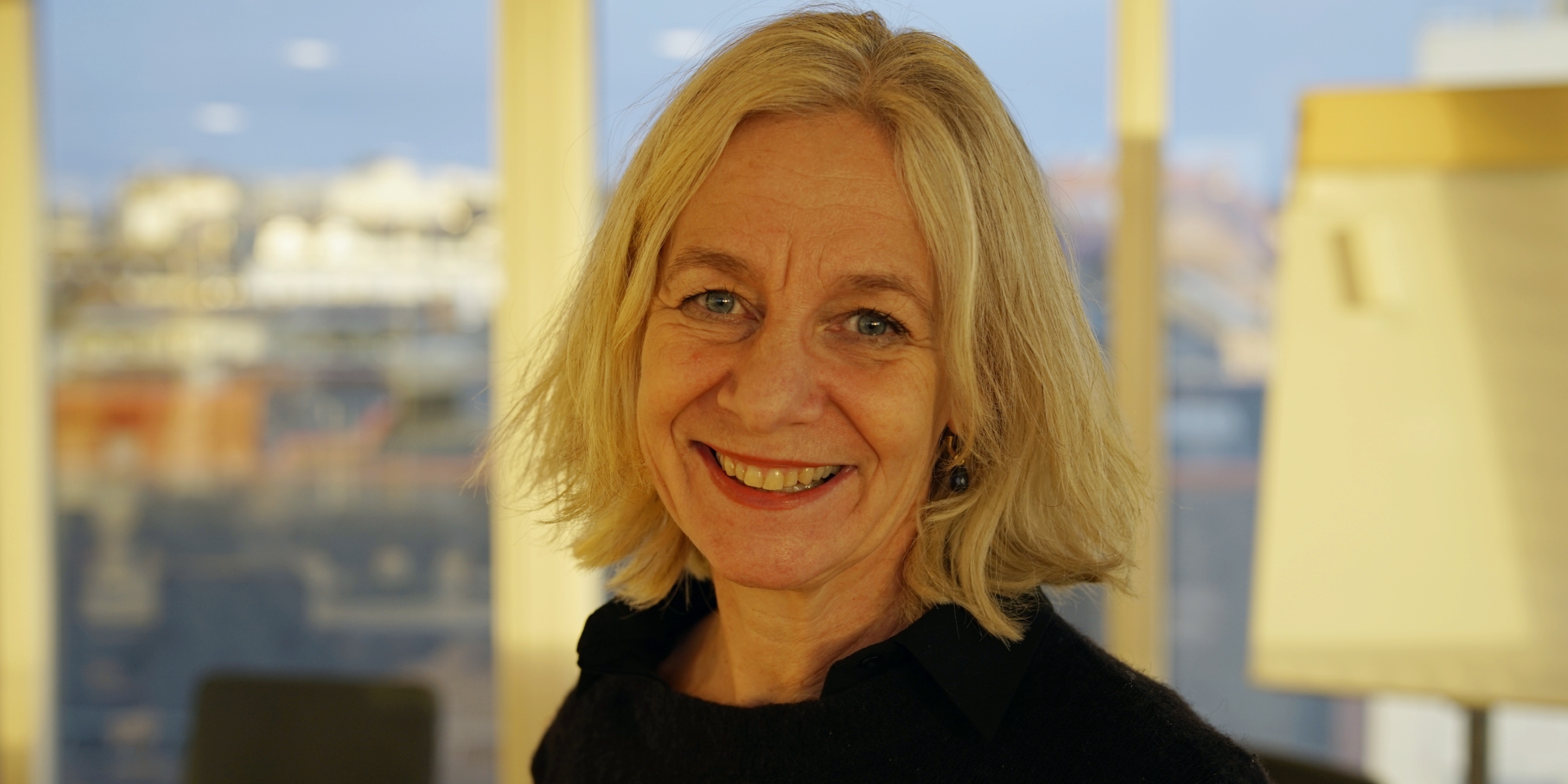 Portrett av Nanna Paaske foran et vindu på et møterom på studiested Pilestredet