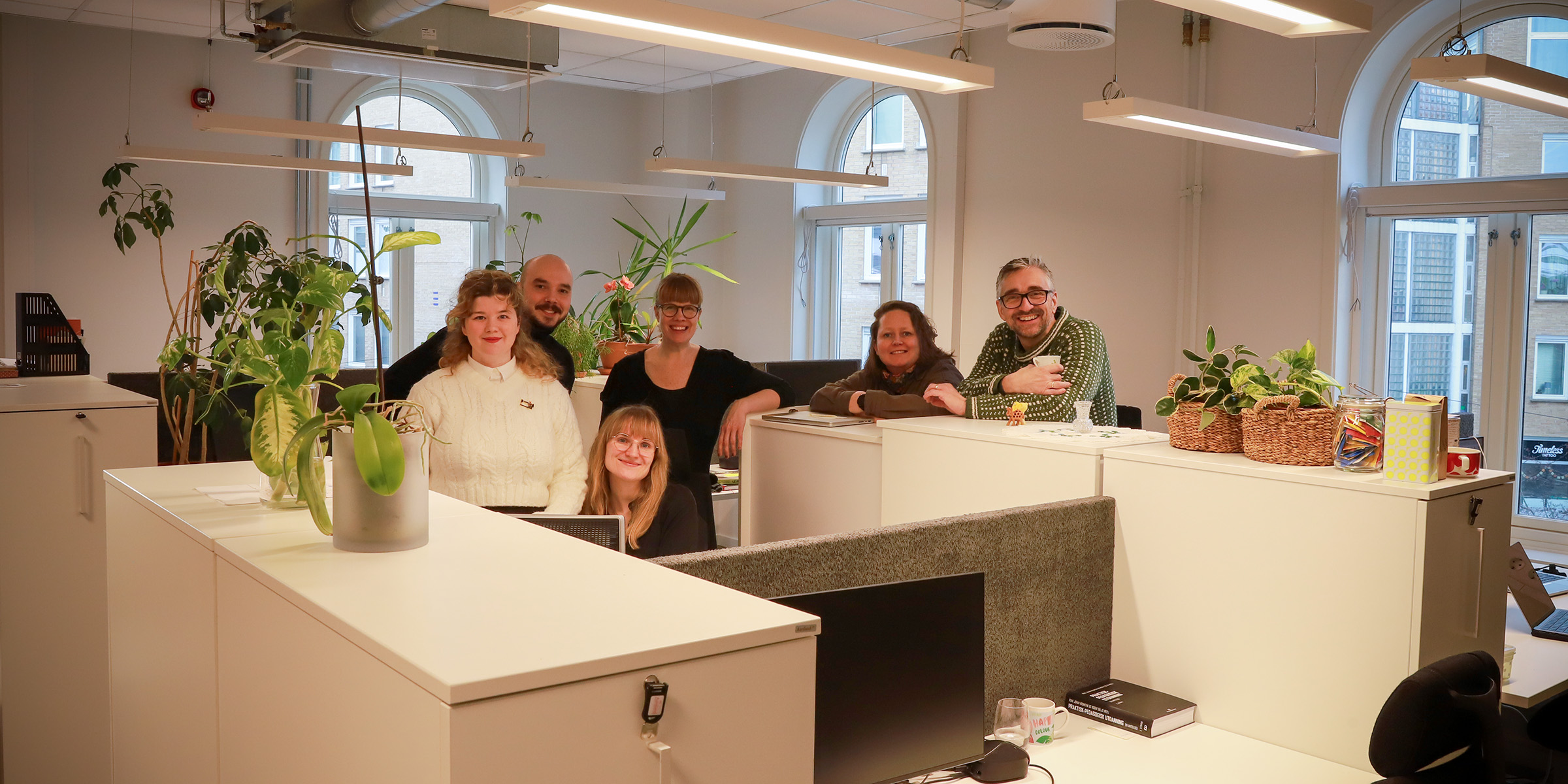 Foto av ansatte ved Institutt for estetiske fag som står i sine nye åpne kontorlokaler.
