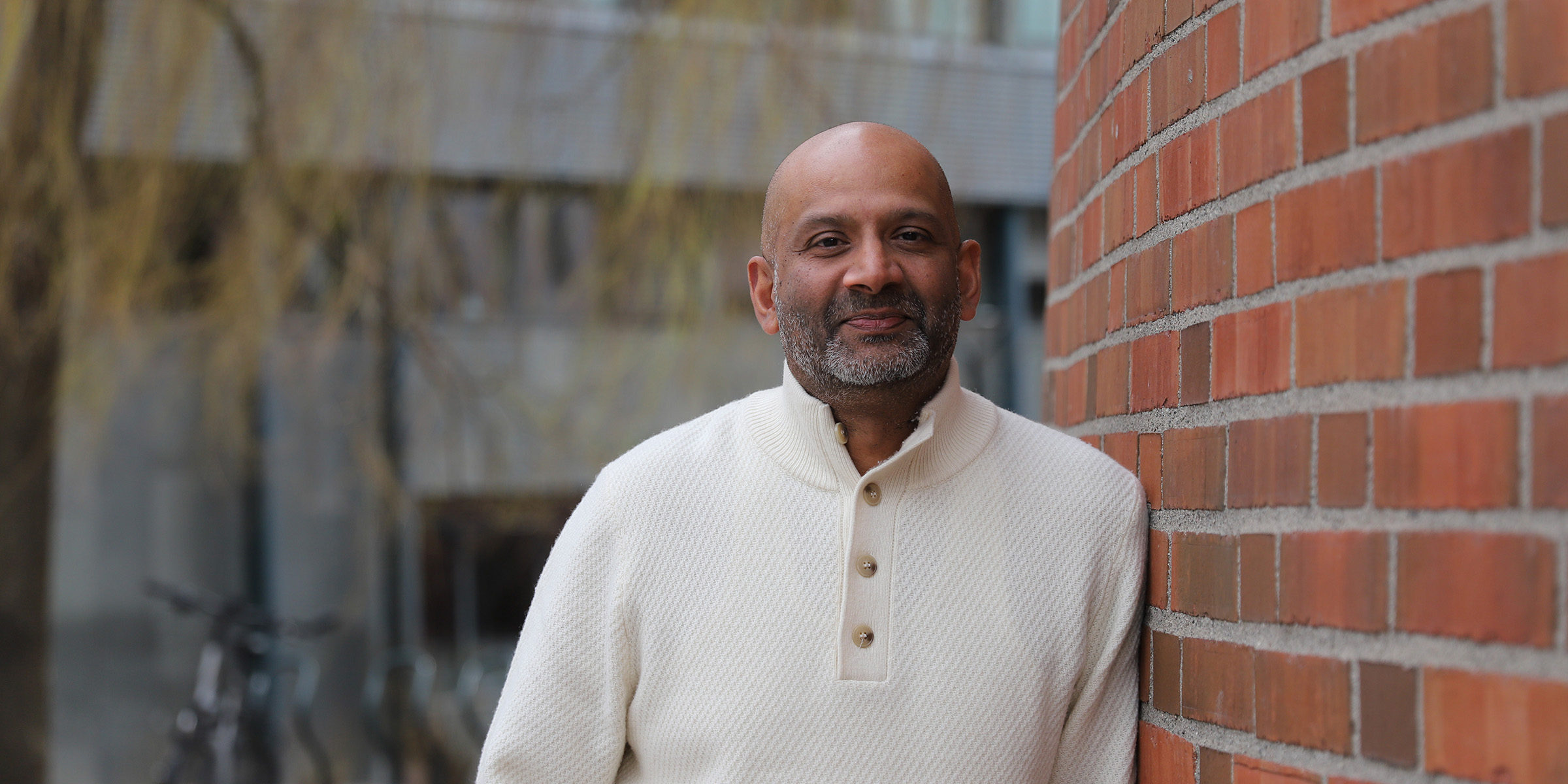 Portrettbilde av Ranjan Chrisanthar, som lener seg inntil en murvegg.