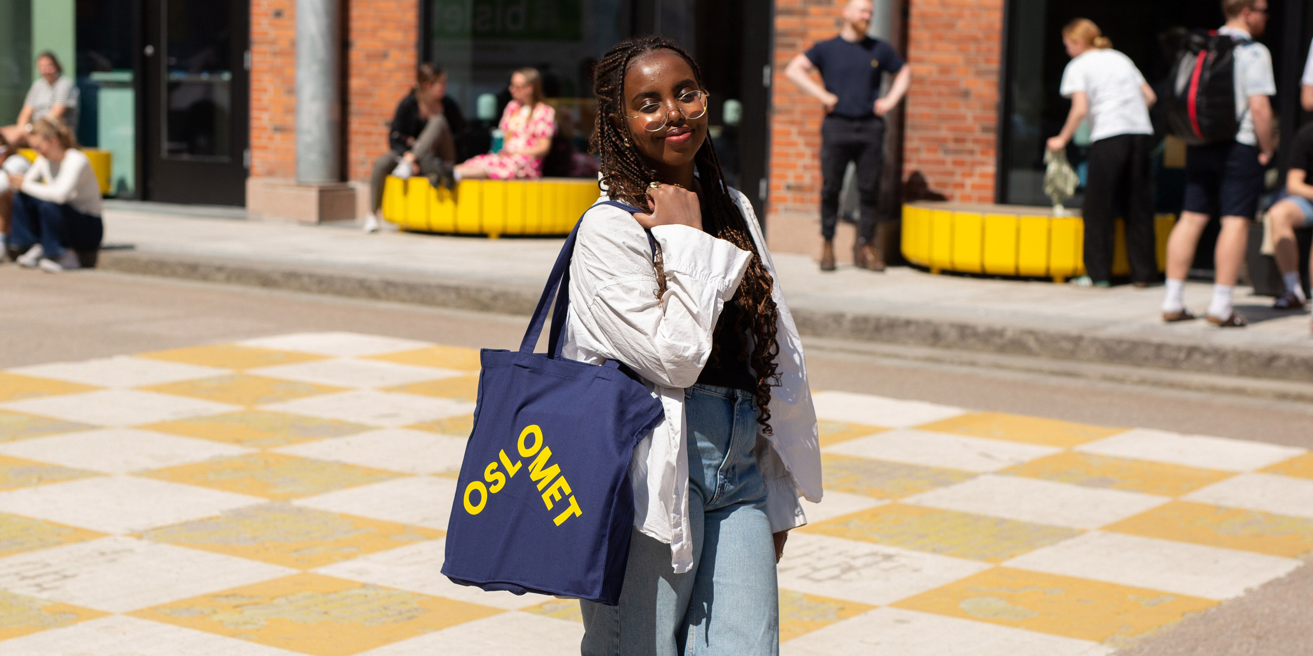 A student holding a ble net over her shoulder. The net is dark blue with a yellow OsloMet logo in front