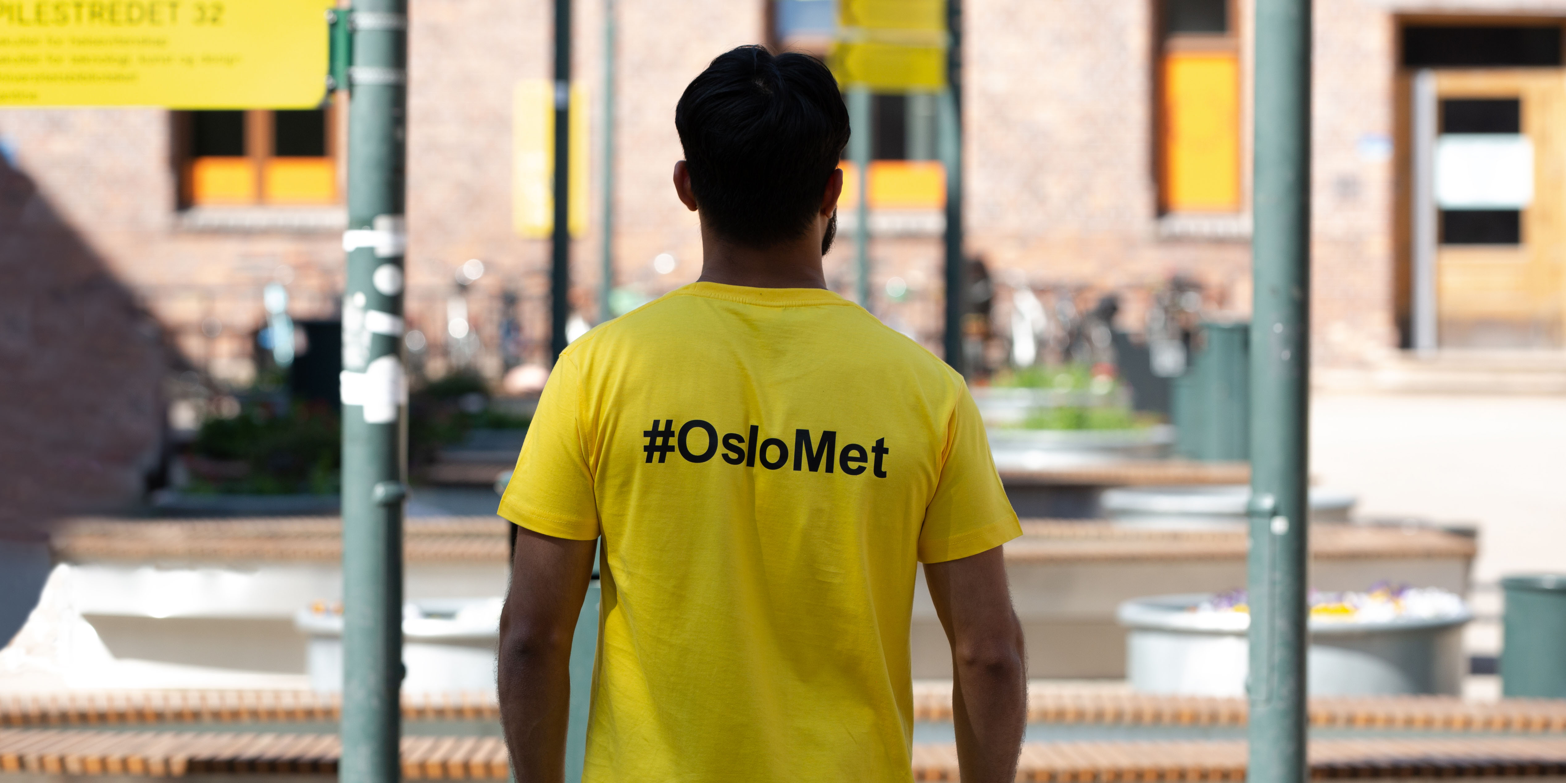 A boy is wearing a yellow t-shirt with the text #OsloMet in black on the back