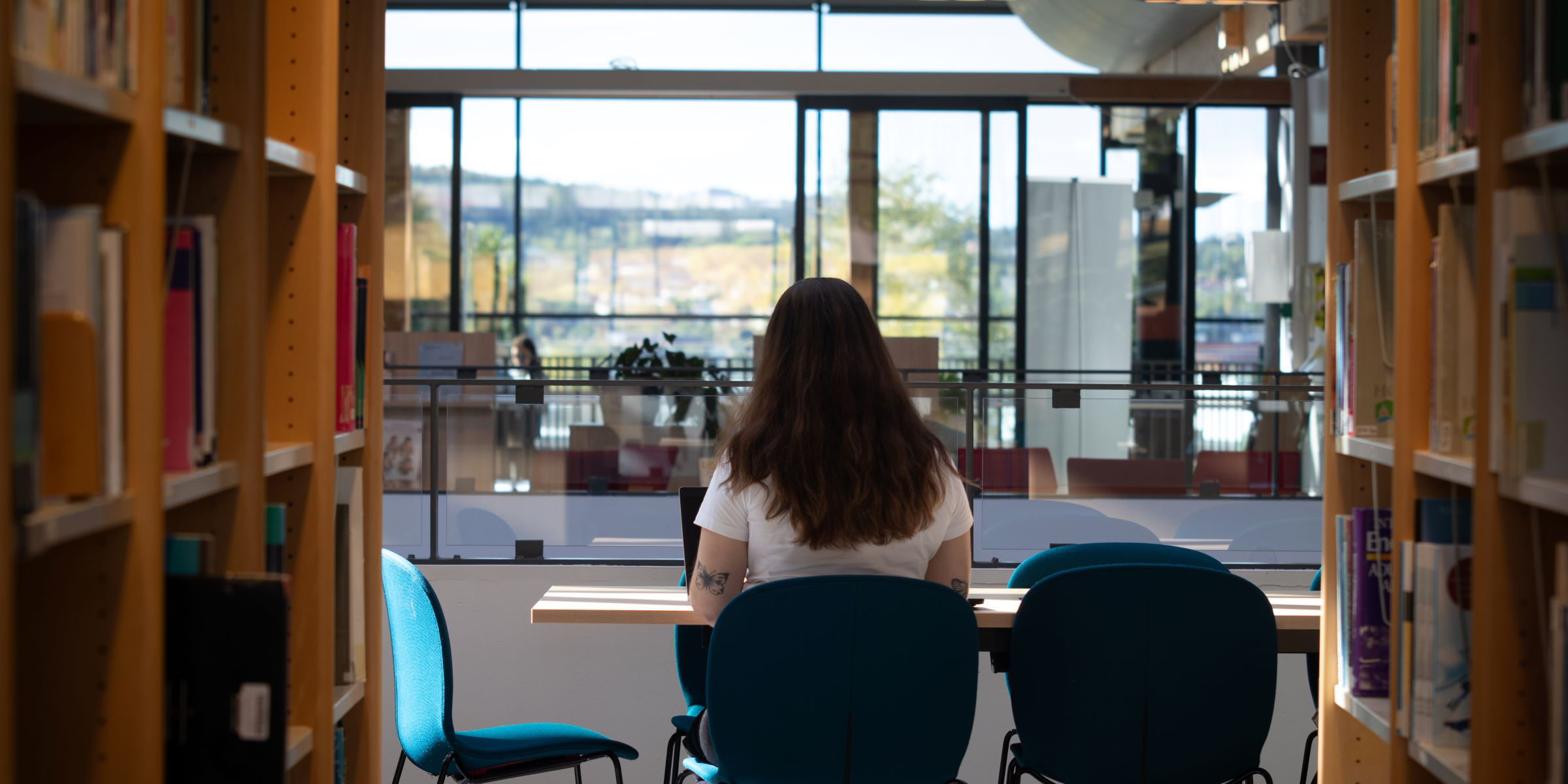 Person som sitter og studerer ved en leseplass i biblioteket på Kjeller.