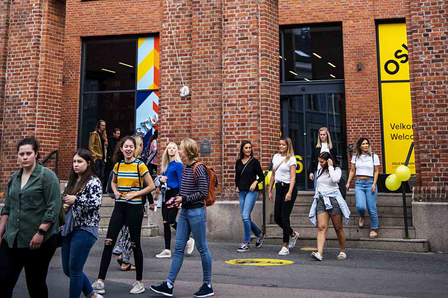 Mange studenter går med inngangen til øvre campus i bakgrunnen.