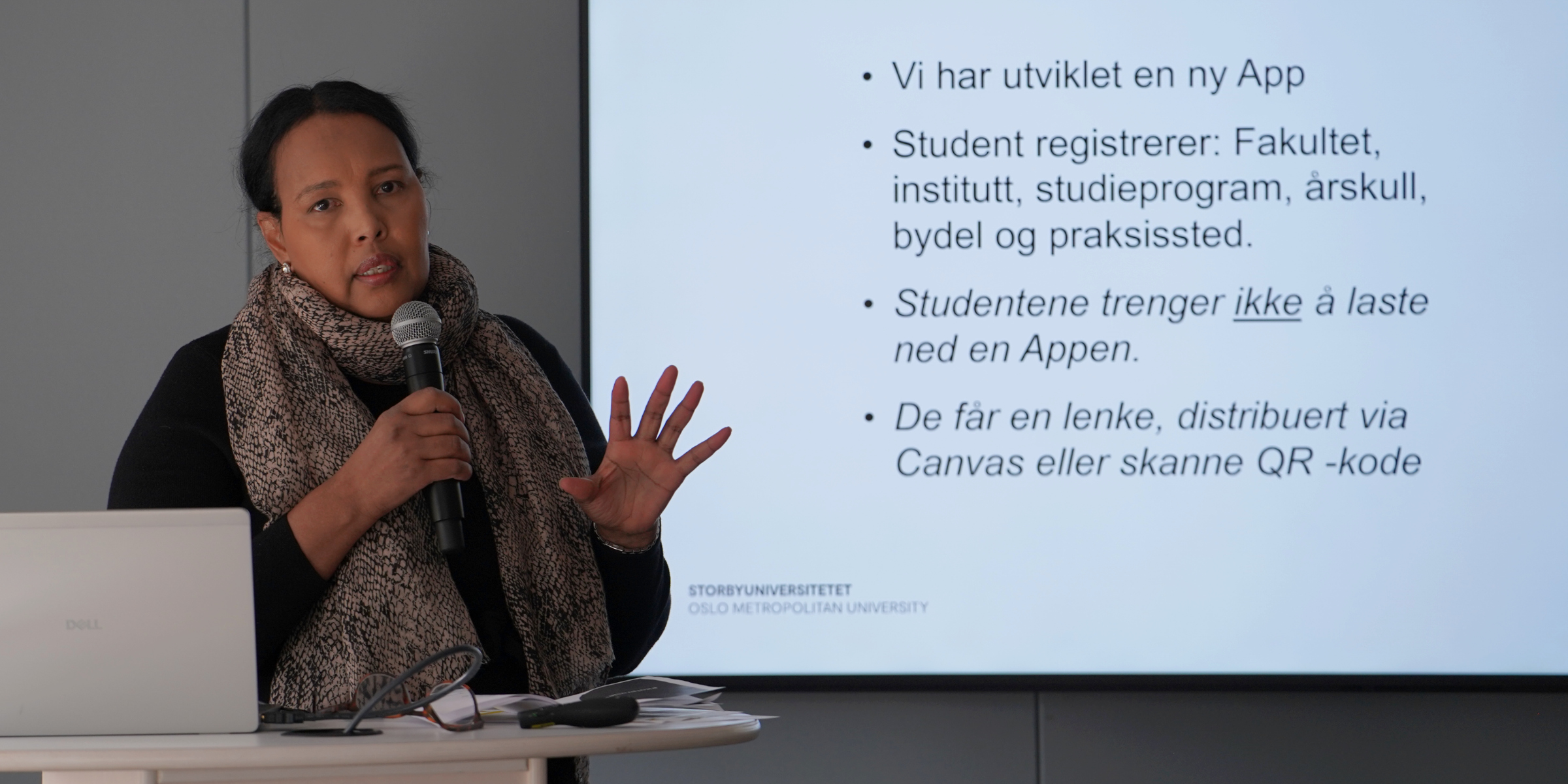 Bilete av Fatima Ali Madar, seniorrådgivar i avdeling for IKT som står med en mikrofon i hånden.